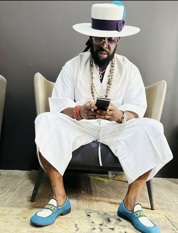 Timaya sitting and on the phone 